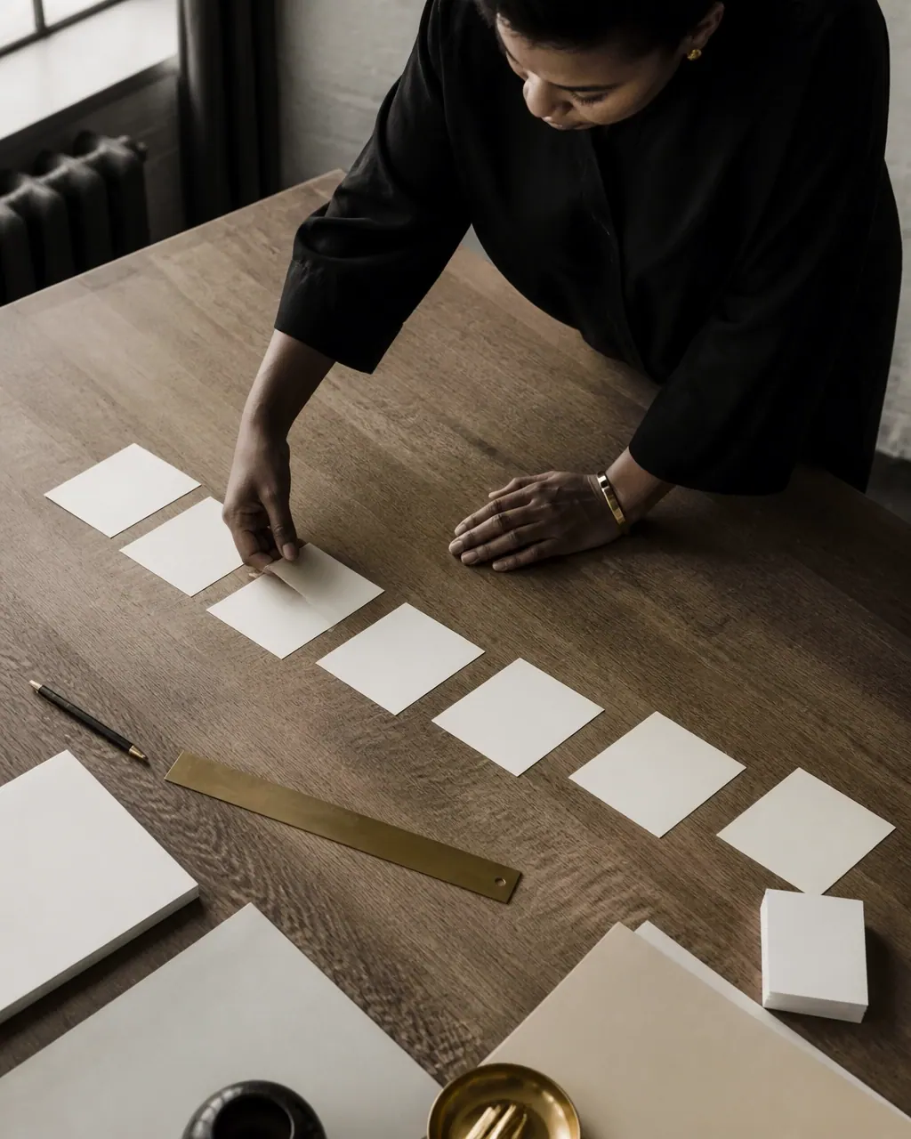 A professional arranges blank cards in sequence on a wooden table to represent strategic planning.